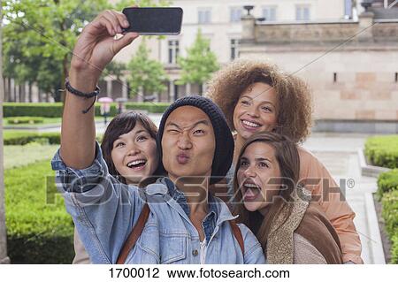 Stock Image - Young man making face while taking selfie with female friends, Berlin, Germany. Fotosearch