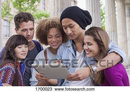 Young man showing digital tablet to multi-ethnic friends View Large Photo Image Stock Image - Young man showing digital tablet to multi-ethnic friends. Fotosearch