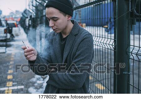 Young man smoking along winter fence View Large Photo Image Stock Image - Young man smoking along winter fence. Fotosearch