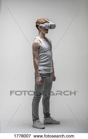 Stock Photo - Young man using virtual reality simulator glasses. Fotosearch