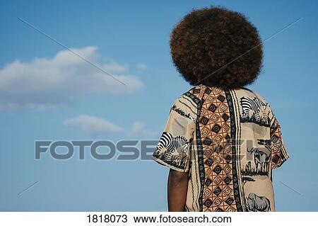 Young man with afro looking up at clouds in blue sky View Large Photo Image Stock Image - Young man with afro looking up at clouds in blue sky. Fotosearch