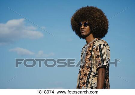 Young man with afro standing against blue sky View Large Photo Image Picture - Young man with afro standing against blue sky. Fotosearch