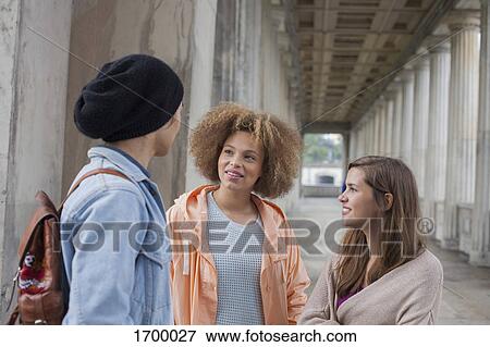 Young multi-ethnic friends talking while standing in corridor, Berlin, Germany View Large Photo Image Stock Photo - Young multi-ethnic friends talking while standing in corridor, Berlin, Germany. Fotosearch