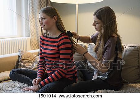 Young woman brushing sister's hair at home View Large Photo Image Picture - Young woman brushing sister's hair at home. Fotosearch