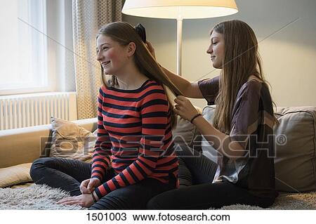 Young woman brushing sister's hair at home View Large Photo Image Stock Image - Young woman brushing sister's hair at home. Fotosearch
