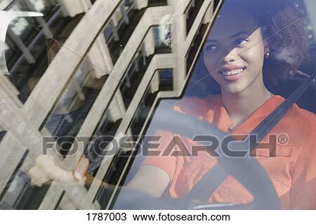 Stock Image - Young woman driving car. Fotosearch