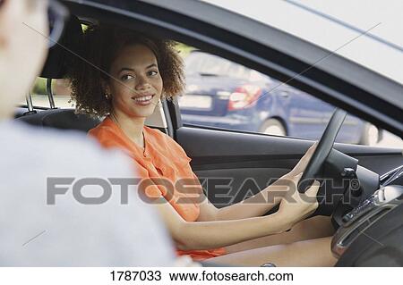 Stock Image - Young woman driving car. Fotosearch