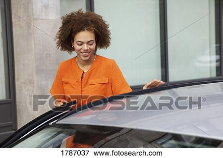 Stock Photo - Young woman getting in car. Fotosearch