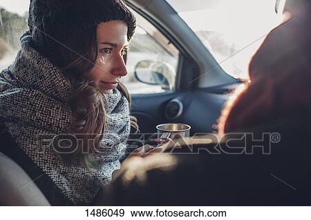 Young woman holding coffee cup while looking at man in car View Large Photo Image Stock Photo - Young woman holding coffee cup while looking at man in car. Fotosearch