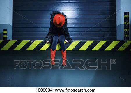 Picture - Young woman in red cowboy boots sitting at edge of loading dock. Fotosearch