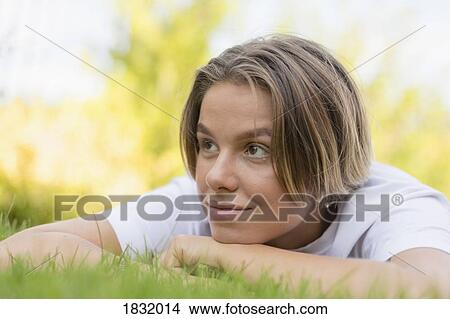 Picture - Young woman laying in grass. Fotosearch