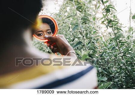 Young woman looking in compact mirror View Large Photo Image Stock Photo - Young woman looking in compact mirror. Fotosearch