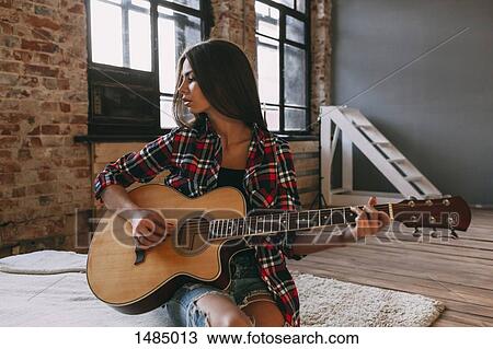 Young woman playing guitar at home View Large Photo Image Stock Image - Young woman playing guitar at home. Fotosearch