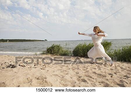 Young woman practicing yoga on sea shore at beach against sky View Large Photo Image Stock Image - Young woman practicing yoga on sea shore at beach against sky. Fotosearch