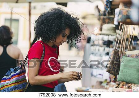 Young woman shopping for jewelry at market stall View Large Photo Image Stock Photo - Young woman shopping for jewelry at market stall. Fotosearch
