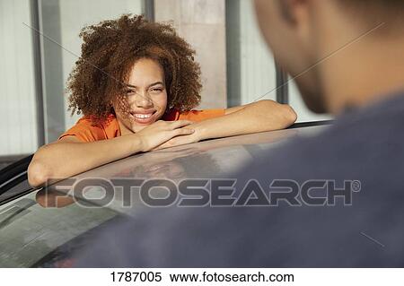 Young woman smiling and talking to man over car View Large Photo Image Stock Photography - Young woman smiling and talking to man over car. Fotosearch