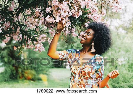 Young woman standing below tree with pink blossoms View Large Photo Image Stock Image - Young woman standing below tree with pink blossoms. Fotosearch