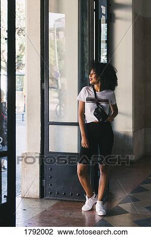 Stock Image - Young woman standing in doorway. Fotosearch