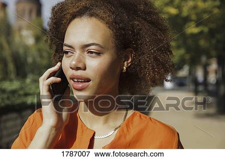 Young woman talking on smart phone on sunny sidewalk View Large Photo Image Stock Photo - Young woman talking on smart phone on sunny sidewalk. Fotosearch