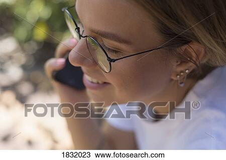 Stock Image - Young woman talking on smart phone. Fotosearch