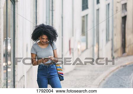 Young woman using smart phone on urban street View Large Photo Image Picture - Young woman using smart phone on urban street. Fotosearch