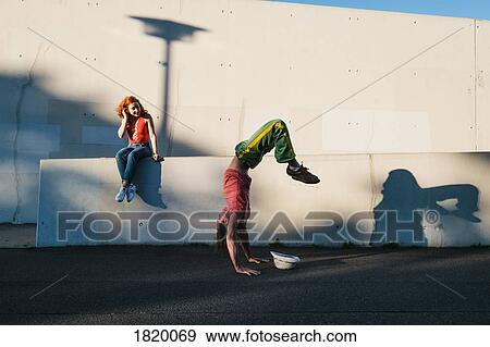 Young woman watching man do handstand along urban wall View Large Photo Image Stock Photo - Young woman watching man do handstand along urban wall. Fotosearch