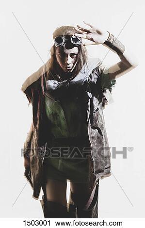 Stock Image - Young woman wearing goggles and jacket gesturing against white background. Fotosearch