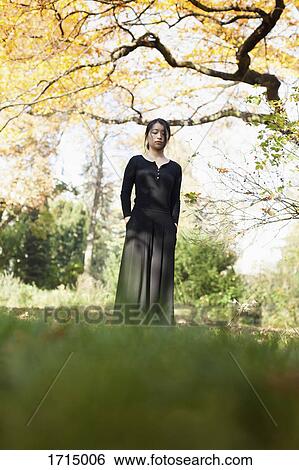 Young woman with closed eyes standing on field against trees at park View Large Photo Image Stock Photograph - Young woman with closed eyes standing on field against trees at park. Fotosearch