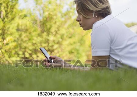 Young woman with headphones using smart phone in grass View Large Photo Image Stock Photo - Young woman with headphones using smart phone in grass. Fotosearch