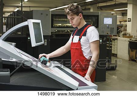Stock Photo - Young worker doing quality check of printout with machinery at printing press. Fotosearch