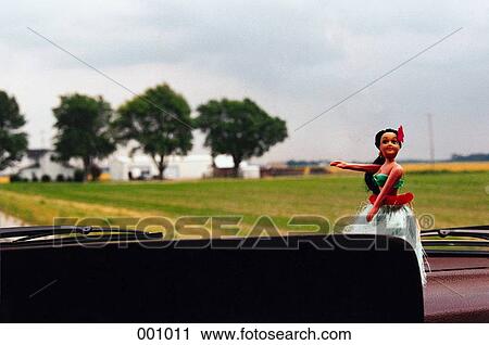 Stock Image - a hawaiian girl figurine sitting on the dashboard of a car. Fotosearch