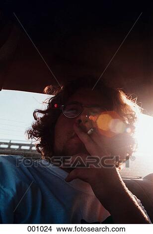 a young man smoking a cigarette in a car View Large Photo Image Picture - a young man smoking a cigarette in a car. Fotosearch
