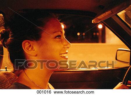 a young, smiling woman driving at night View Large Photo Image Stock Photograph - a young, smiling woman driving at night. Fotosearch