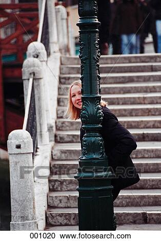 a young, smiling woman peeking out from behind a lamppost View Large Photo Image Stock Image - a young, smiling woman peeking out from behind a lamppost. Fotosearch
