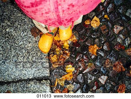 Stock Image - child's boots on wet cobblestone. Fotosearch
