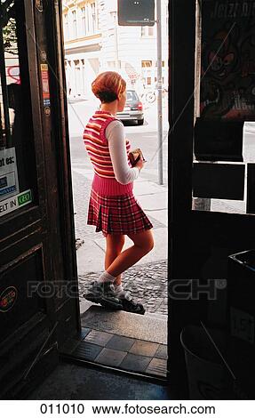 Stock Image - girl standing in a shop doorway. Fotosearch
