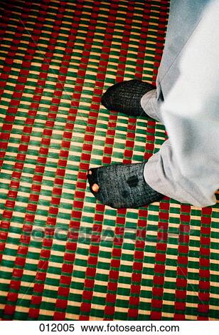 Stock Photography - person standing on checked carpet with hole in sock. Fotosearch