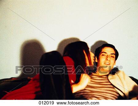 Stock Photo - woman blowing in man's ear on couch. Fotosearch
