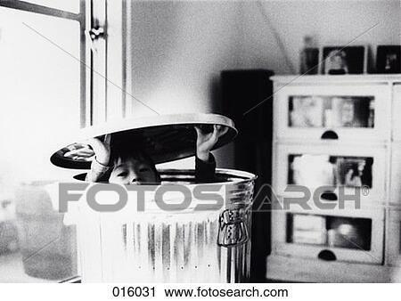 Stock Image - a child peeking out from a metal garbage can. Fotosearch