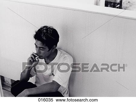 a man smoking a cigarette, leaning against a wall View Large Photo Image Stock Photography - a man smoking a cigarette, leaning against a wall. Fotosearch