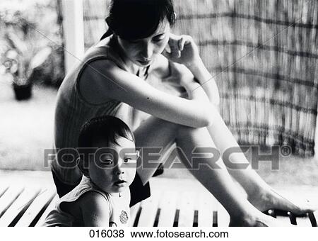 a woman sitting next to and watching a baby View Large Photo Image Stock Photo - a woman sitting next to and watching a baby. Fotosearch