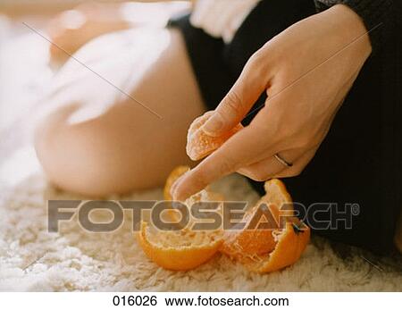 Stock Photograph - woman's hand holding peeled tangerine. Fotosearch