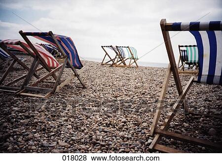 lounge chairs being blown by the wind on a beach View Large Photo Image Stock Photo - lounge chairs being blown by the wind on a beach. Fotosearch