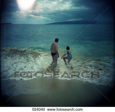 Stock Image - A man and woman splashing in the waves. Fotosearch