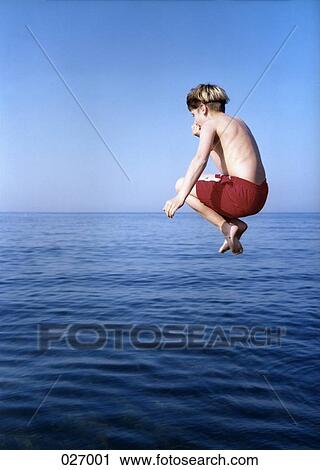 A boy in midair, jumping in the water View Large Photo Image Stock Image - A boy in midair, jumping in the water. Fotosearch