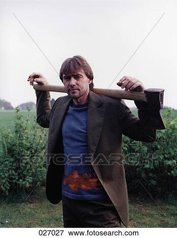 A man in the countryside holding an axe over his shoulders View Large Photo Image Stock Photo - A man in the countryside holding an axe over his shoulders. Fotosearch