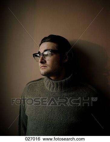 Stock Photograph - A man leaning against a wall, staring off. Fotosearch