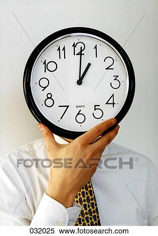 A businessman holding a clock in front of his face View Large Photo Image Stock Photography - A businessman holding a clock in front of his face. Fotosearch