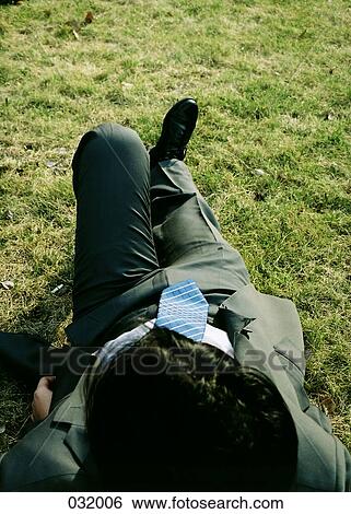 A businessman lying in the grass View Large Photo Image Stock Photograph - A businessman lying in the grass. Fotosearch