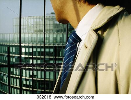 A businessman peering down from a building View Large Photo Image Stock Photo - A businessman peering down from a building. Fotosearch